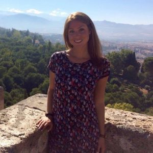 A photo of Jordana Goldman, with trees and buildings in the distance.