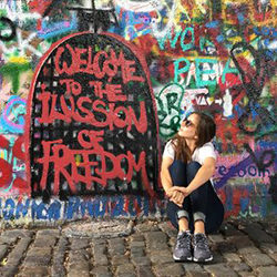 A person is sitting on the ground, looking up at a a painted wall.