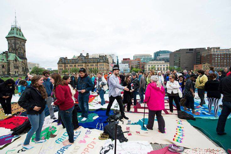 Many people gathered on Parliament Hill, standing on top of blankets on the ground, which have been designed.
