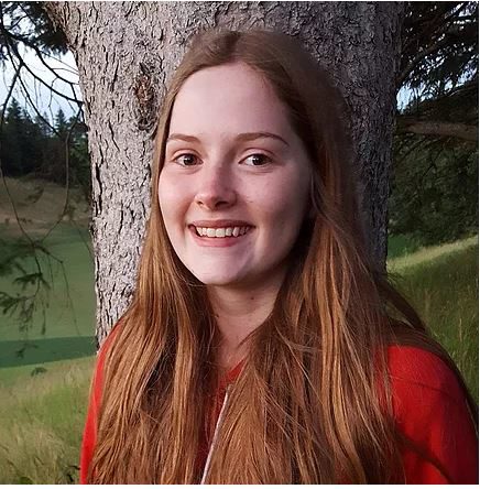 A photo of Christine Drader, with a tree in the background and a field visible.
