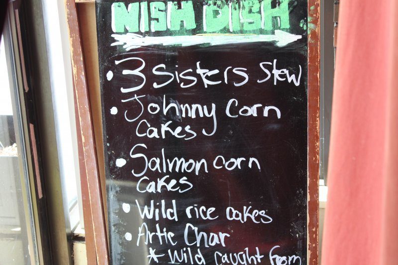 A sign that says 'NISH DISH' in green, with five different menu options written in white below.
