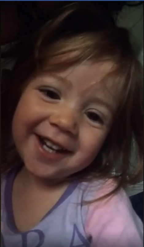A close up photo of a child, smiling at the camera.